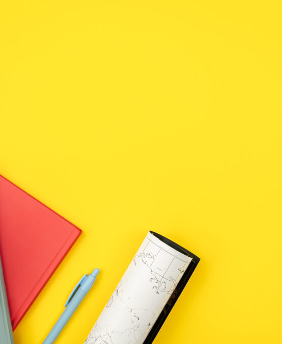 Notebooks, globe and map on a yellow background, flat lay.
