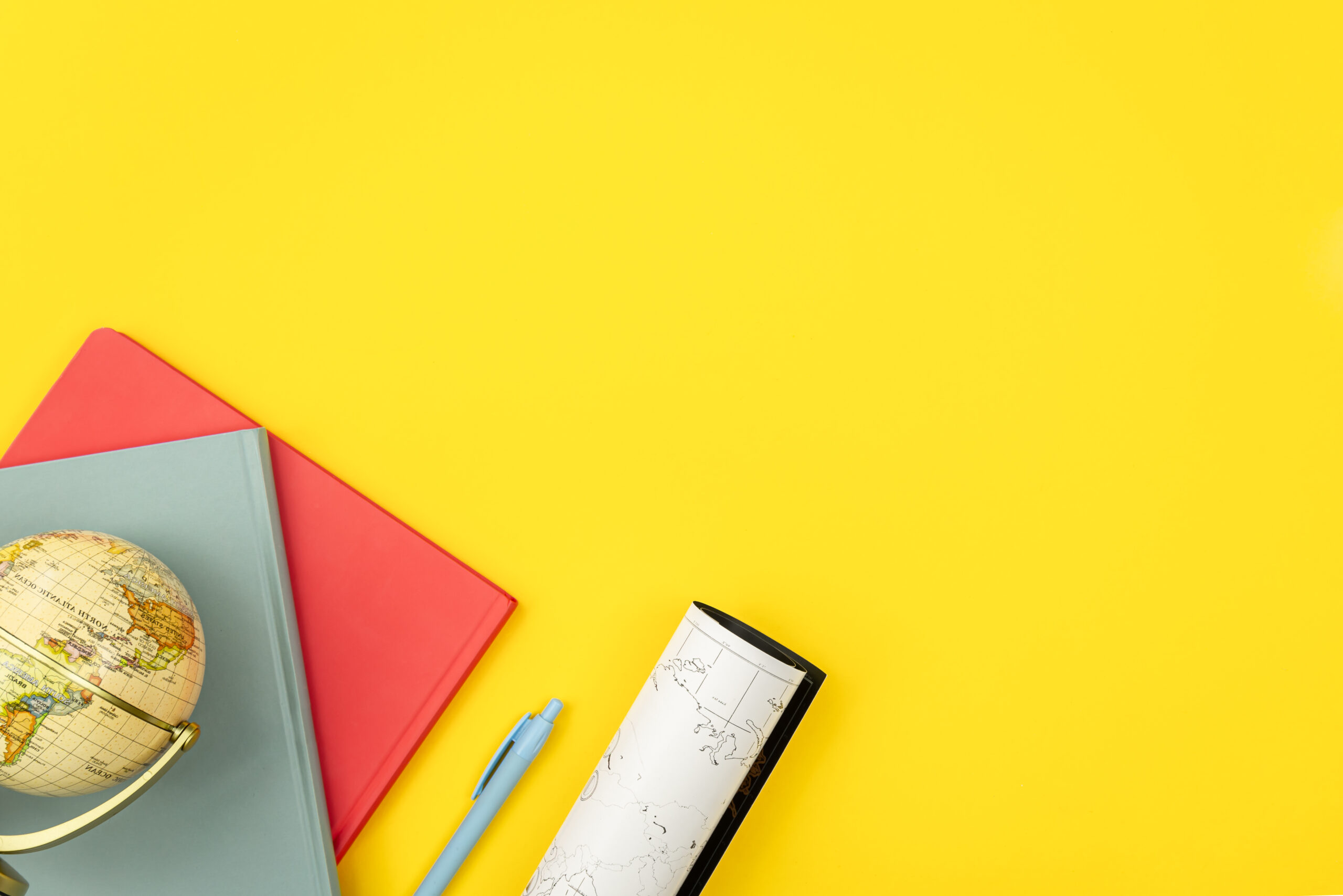 Notebooks, globe and map on a yellow background, flat lay. Notebooks, globe and map on a yellow background, flat lay.